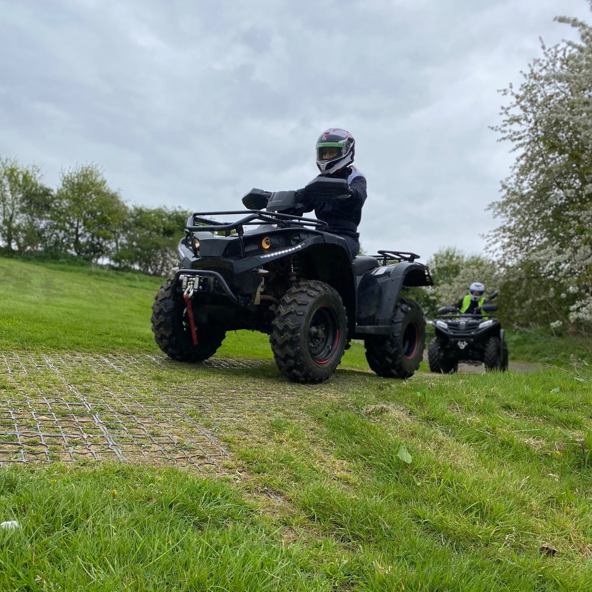 two people on quad bikes riding in a field